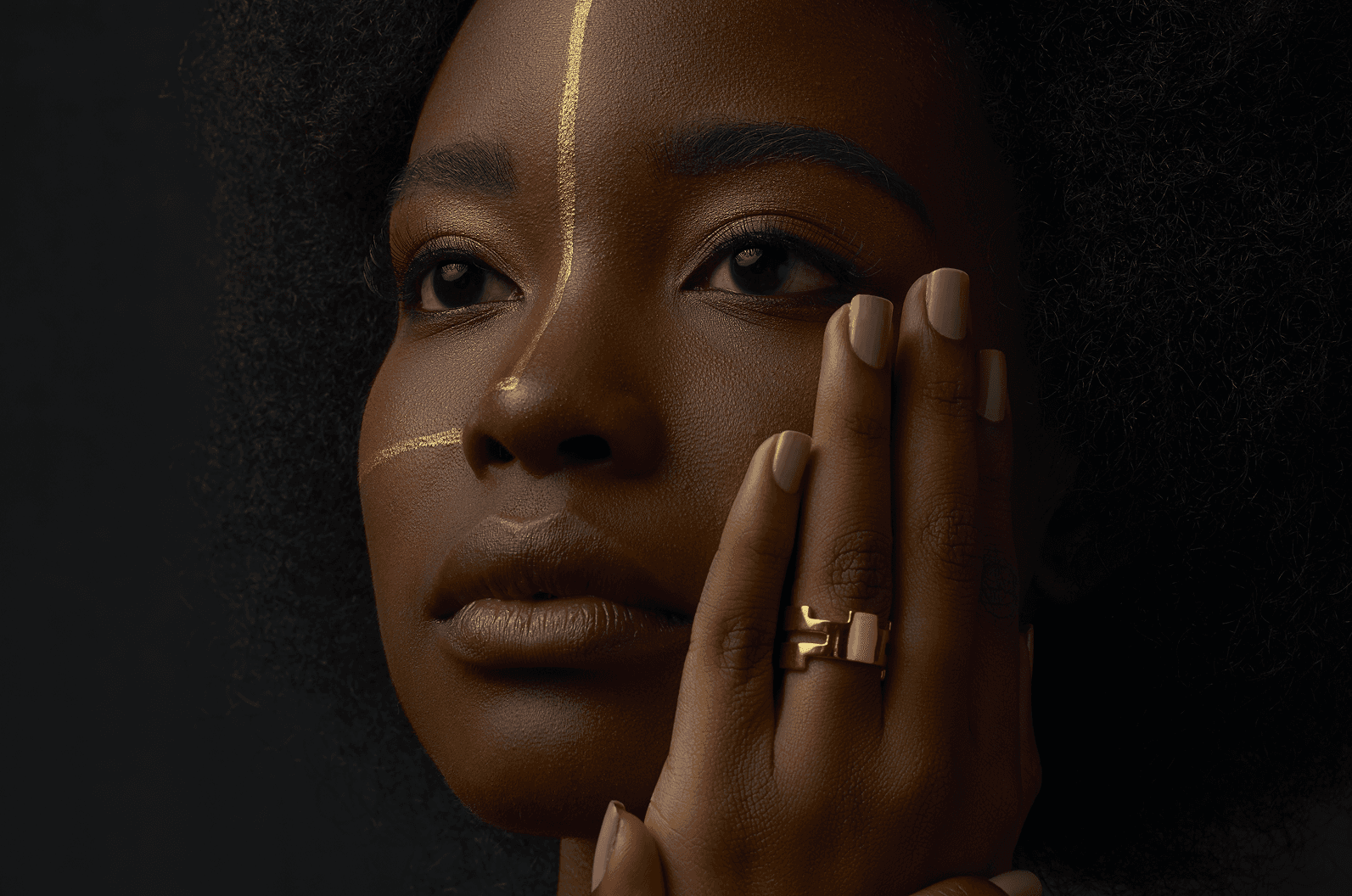 Model with a painted gold facial line wearing the two-band El Abrazo ring